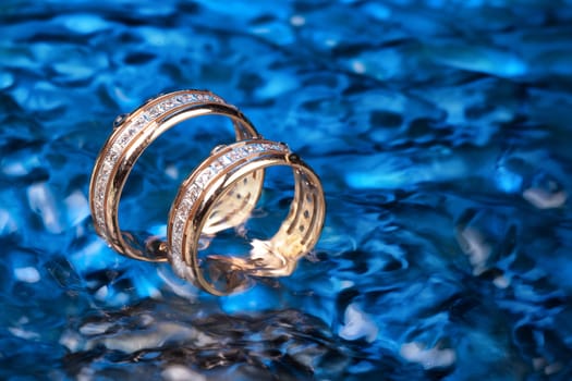 Two engagement golden rings in the ater with air bubbles