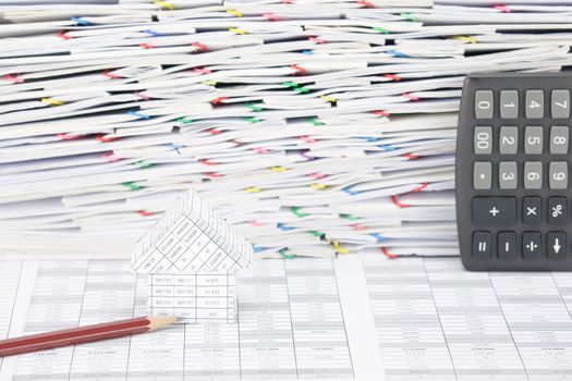 House with brown pencil on finance account have calculator place vertical and overload of confused paperwork with colorful paperclip as background.
