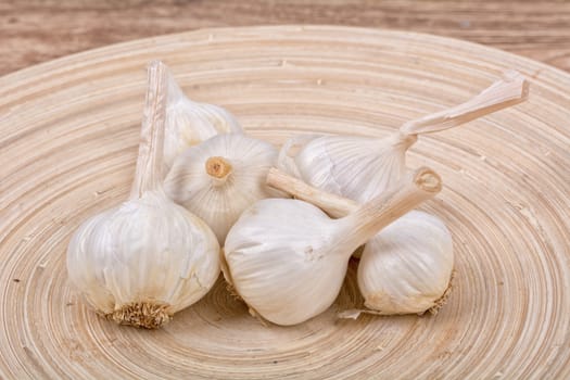 Garlic on a wooden bowl and a wooden background
