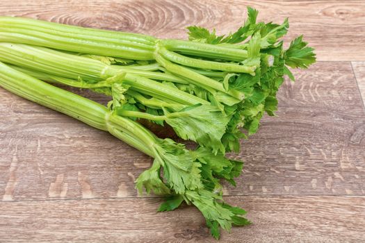 The green leaves of celery on a brown wooden background