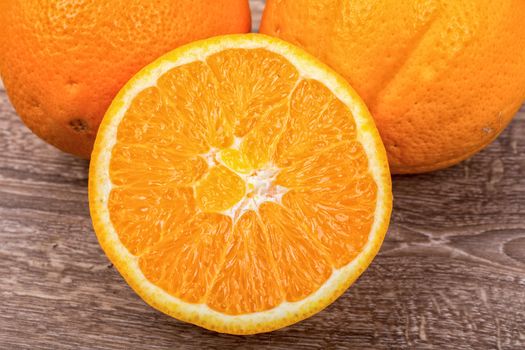 The orange oranges on a brown wooden background