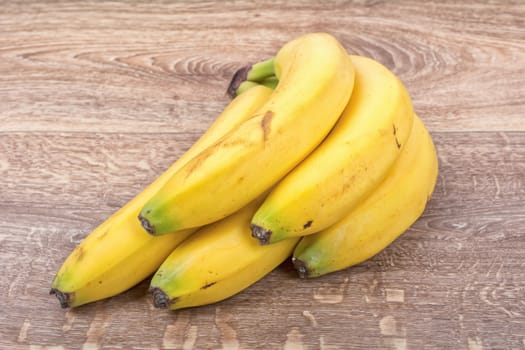 A clump of yellow bananas on a brown wooden background