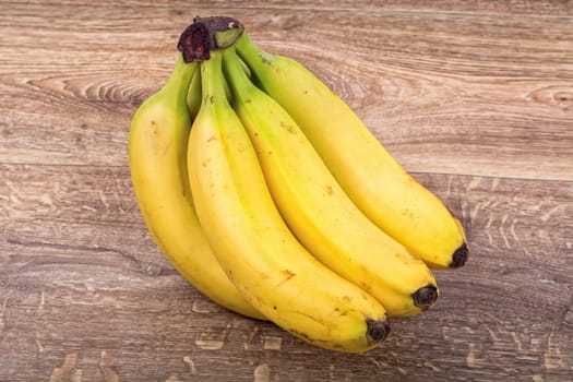 A clump of yellow bananas on a brown wooden background