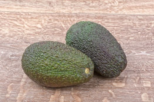 Two of avocado on a brown wooden background