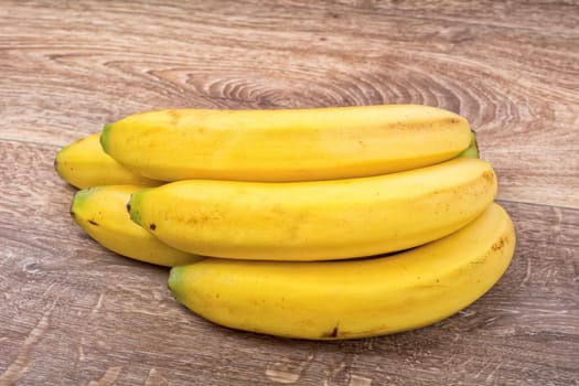 A clump of yellow bananas on a brown wooden background