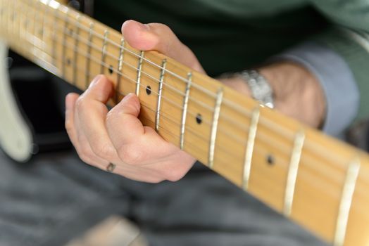 Detail of an electric guitar. Hands moving on the keyboard. Close up. Particularly small and out of focus.