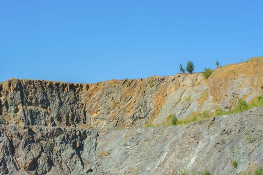 Abandoned Quarry with blue sky and shrubs on top