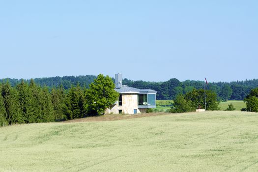 House standing on the edge of the forest with blue sky