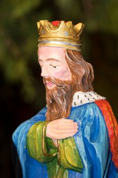 Colored wood sculpture of King with blurred background.