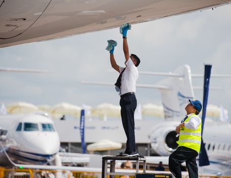 Singapore - February 16, 2016: Exhibition staff removing stains from the body of a Qatar Airways Airbus A350 XWB before the opening of Singapore Airshow at Changi Exhibition Centre in Singapore.