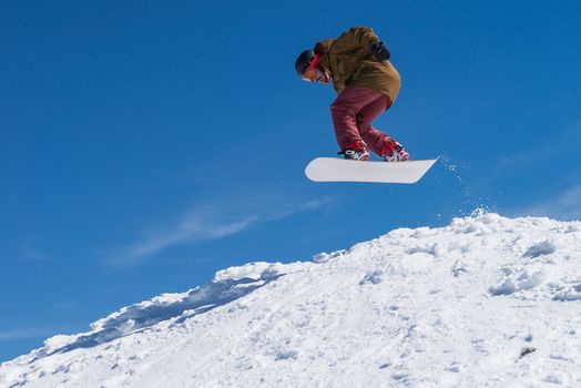 Snowboarder executing a radical jump against blue sky.