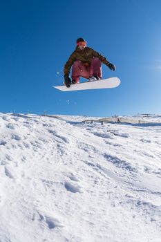 Snowboarder executing a radical jump against blue sky.