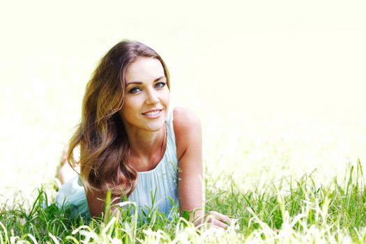 beautiful young woman in blue dress lying on grass