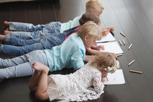 Group of cute children drawing with colorful pencils on floor