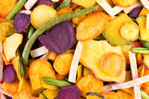 Background food texture of organic healthy veggie chips made form an assortment of colorful dried sliced vegetables in a full frame view