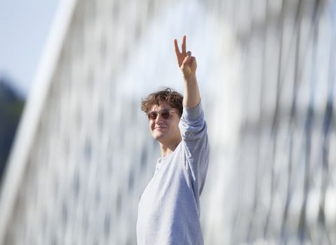 Young Man Standing on the Bridge Making V-sign
