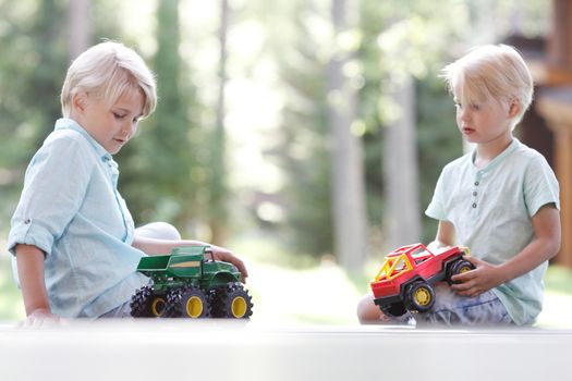 Little brothers playing with toy cars outdoors