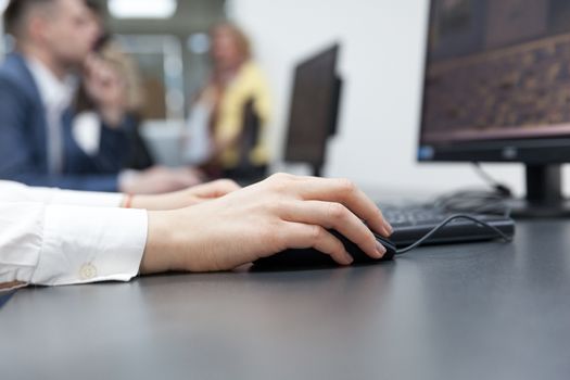 Close up of female hand on mouse while typing on keyboard