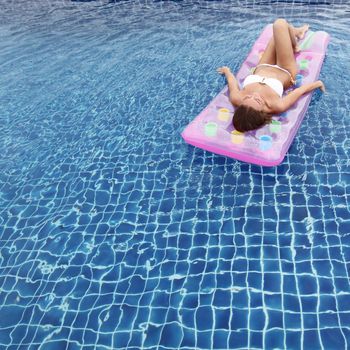 Woman relaxing in a pool floating on water bed