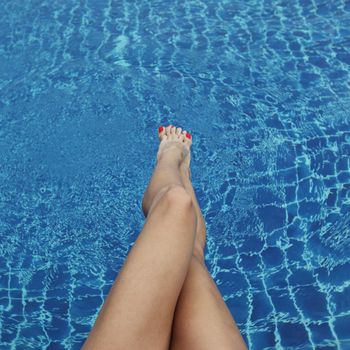 Female legs in the pool water close up