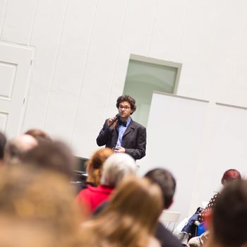 Speaker Giving a Talk at Business Meeting. Audience in the conference hall. Business and Entrepreneurship. Copy space on white board.