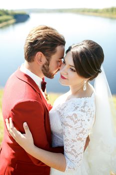 Bride and groom, lovely couple. Stylish man with mustache, beard and bow tie, in red suit. Wedding Color Marsala. Vertical.