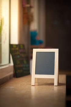 Small A-frame black board with blank area for text or message on wood bar in cafe wih low key scene