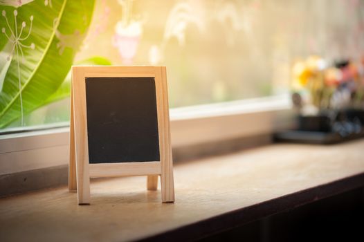 Small A-frame black board with blank area for text or message on wood bar in cafe