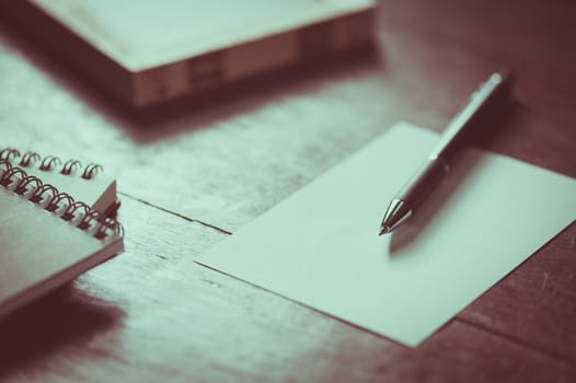 Blank paper on wood table with notebooks on wood table with vintage filter effect