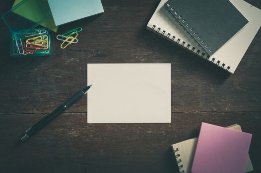 Notepad with blank area for text or message on wood table with low key scene and vintage filter effect