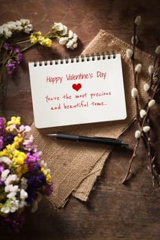 "Happy valentine's day You're the most precious and beautiful to me" is written on notebook on wood table with low key scene