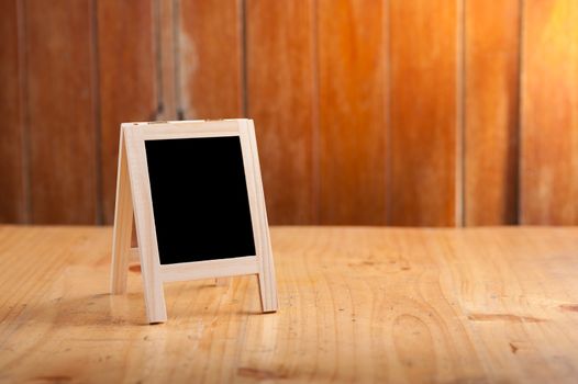 Small A-frame black board with blank area for text or message on wood table