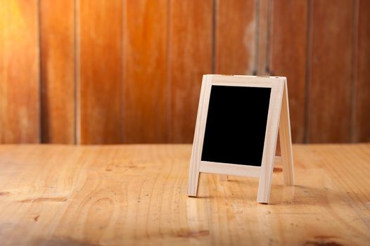 Small A-frame black board with blank area for text or message on wood table