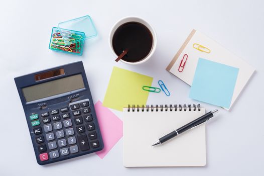 Opened notebook with blank space for text or message, sticky paper, calculator, and take away coffee cup on office table
