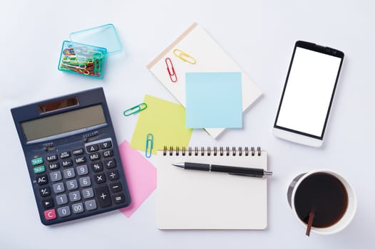 Opened notebook with blank space for text or message, sticky paper, calculator, and take away coffee cup on office table