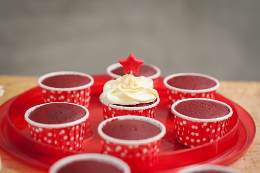 The action of making red velvet cupcakes. one suceed red velvet cupcake with cream cheese and fondant.