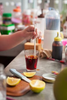 The process of making Thai lemon tea. Woman left hand stir hot tea to dissolve and mix ingredients together.