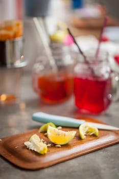 Pieces of sliced lemon on wood board on concrete bar in cafe with low key scene