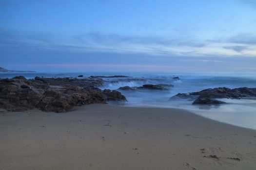 Long exposure of sunset over rocks, giving a mist like effect over ocean in Laguna Beach, California, United States