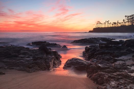 Long exposure of sunset over rocks, giving a mist like effect over ocean in Laguna Beach, California, United States