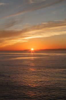 Orange sunset over Catalina Island in a calm ocean in Laguna Beach, Southern California, United States