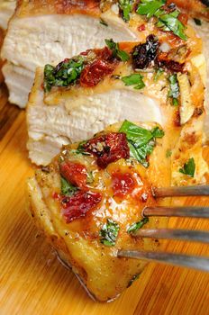 Slices of roasted chicken breast with spices on a wooden board