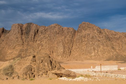 Golden hour in the mountains on the desert in Egypt. Later afternoon dark blue sky with some clouds.