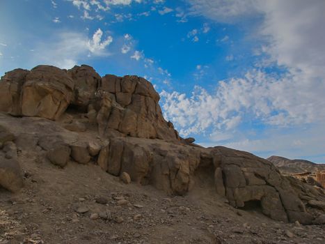 Rounded edges of the rocks in the egyptian desert. Blue sky with intense white clouds.