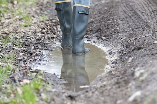 Man with rubber boots walking on rural path