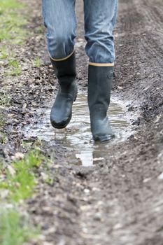 Man with rubber boots walking on rural path