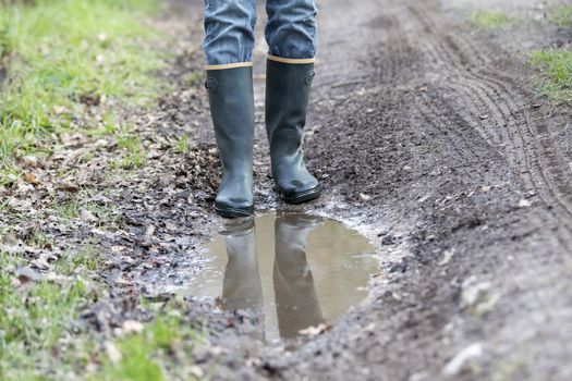 Man with rubber boots walking on rural path