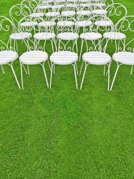 Green lawn with rows of empty white chairs. Space for text.