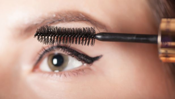 woman paints the eyelashes mascara, eye closeup