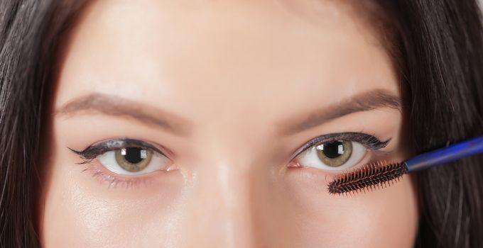 woman paints the eyelashes mascara, eyes closeup